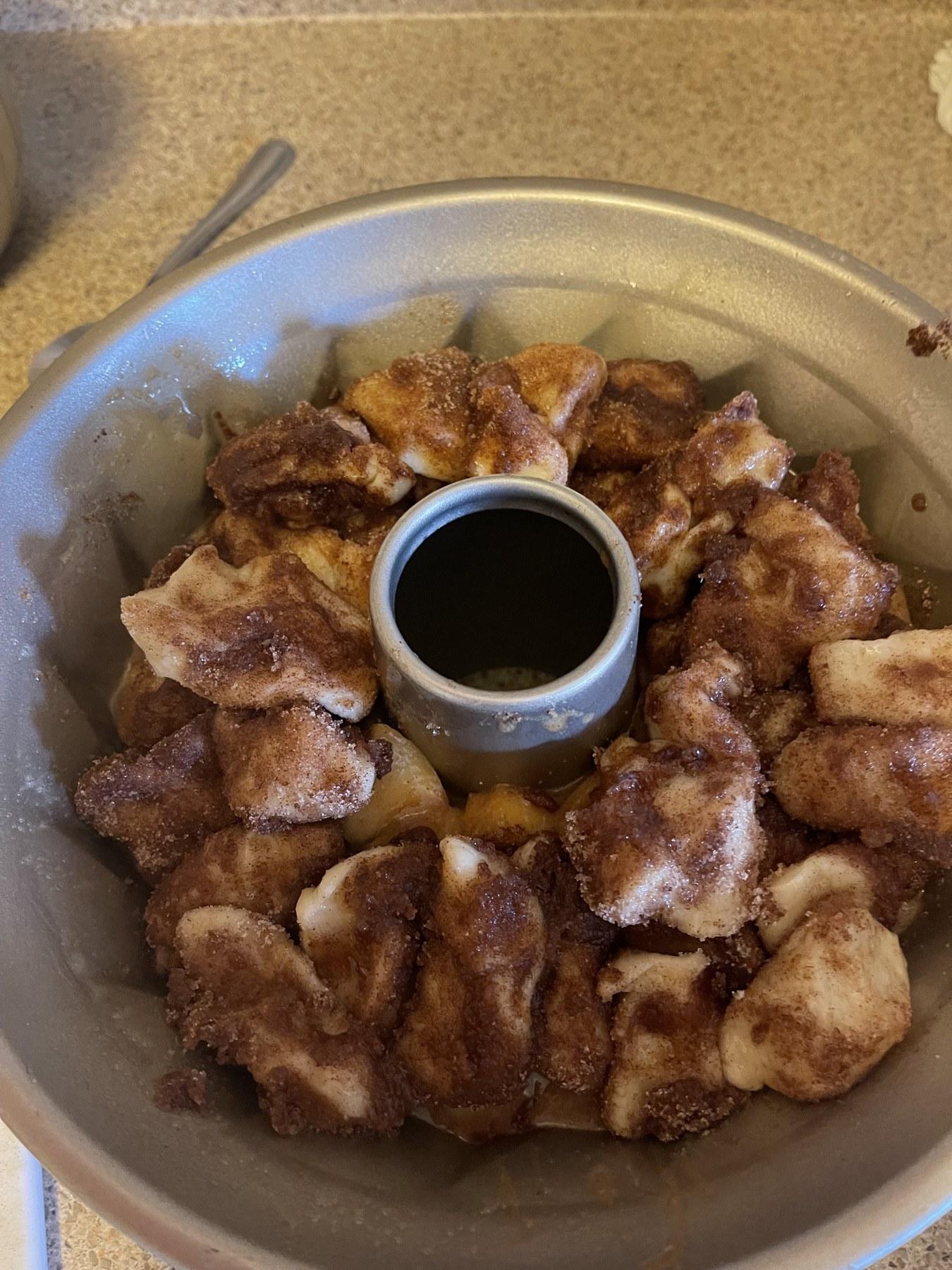 Bundt pan filled with cinnamon-sugar dough pieces and apple filling, ready to bake