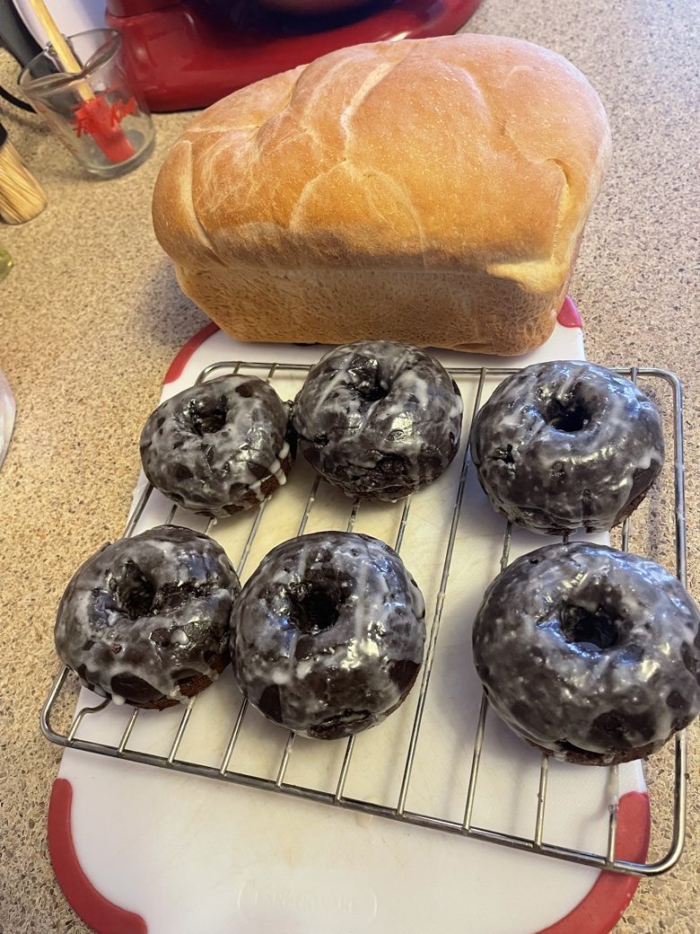 Six chocolate-glazed donuts cooling on a wire rack