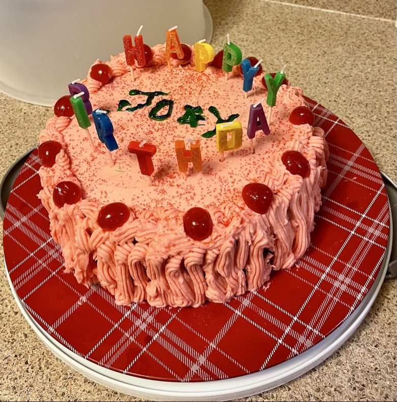 Pink birthday cake with candles and cherries